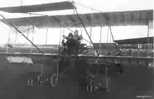 Авиатор с пассажиром на биплане перед подъемом во время праздника