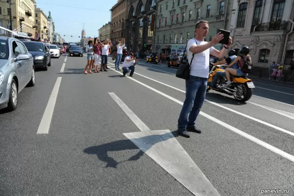 Passers-by photograph a column of bikers