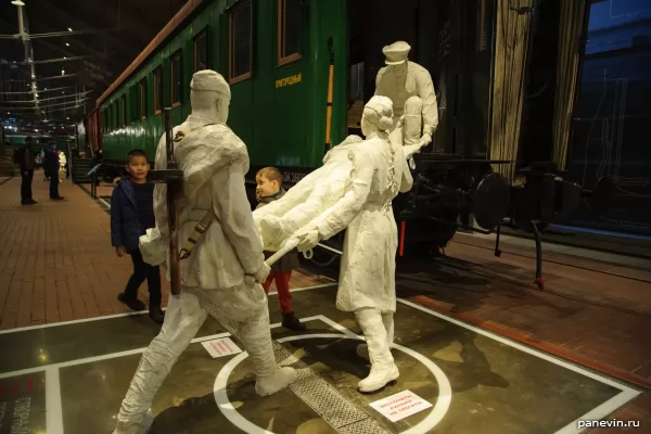 Бойцы и медсестра грузят раненого в санитарный поезд