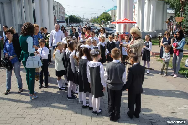 A tour guide in 17th century archery clothes rubs schoolchildren for history