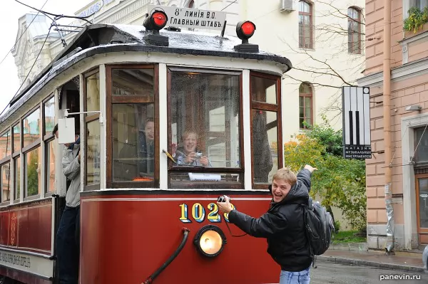 People are happily photographed with a historic tram.